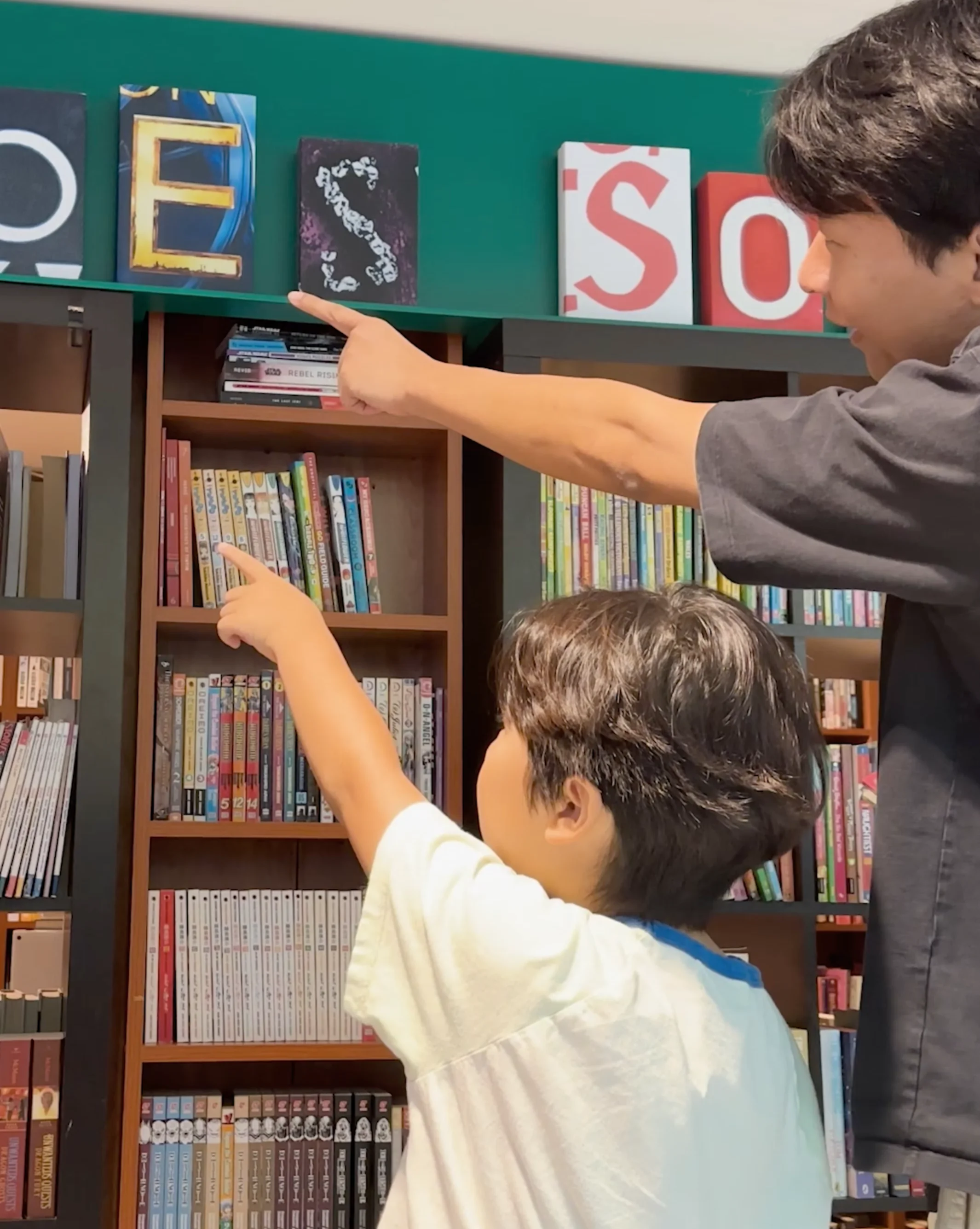 Visitors pointing at House of Prose letter tiles above the shelves