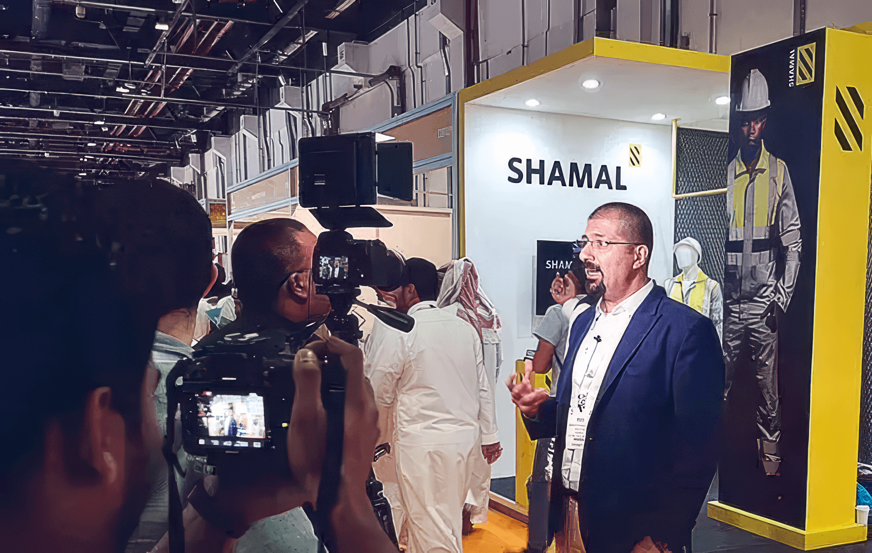 Shamal Workwear trade show booth featuring branded stand graphics and a mannequin in high-visibility workwear, showing how the lightweight extreme-climate gear was presented publicly. Shamal Workwear exhibition booth with branded signage, product display, and with Samer Choucair, Director at CE-Creates standing in front at a trade show.